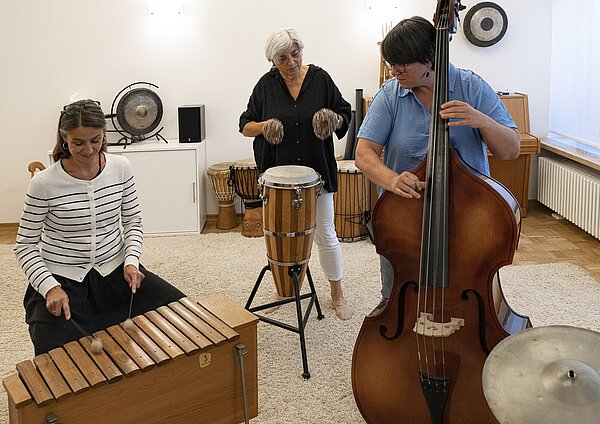 Gruppenfoto von musikspielenden Personen mit Instrumenten