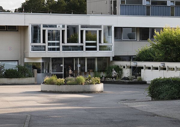 Eingang der Klinik mit Pflanzenrondell davor